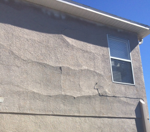 Exterior inspection image of cracked stucco on wood frame