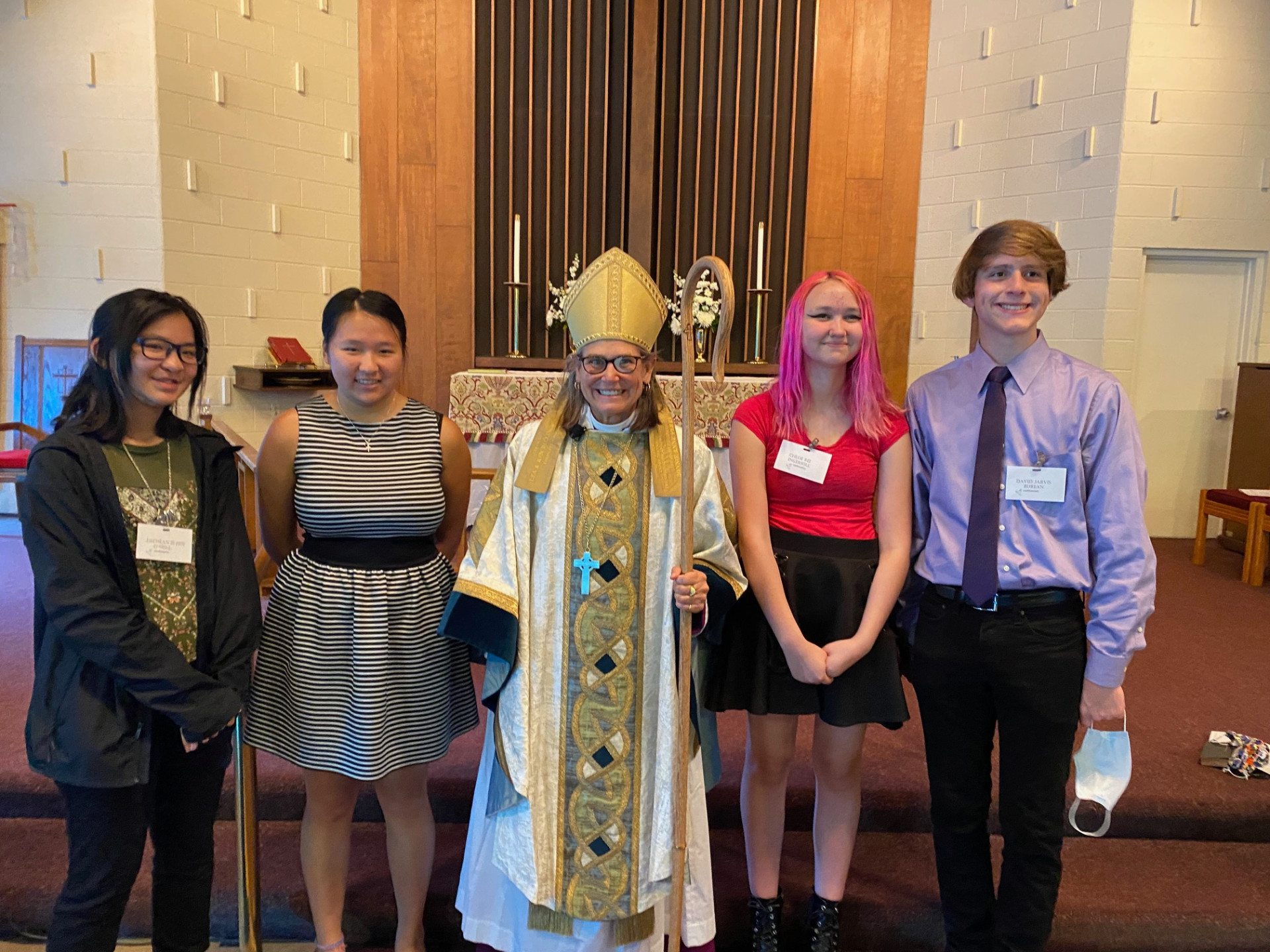 A celebratory scene capturing young individuals and a smiling clergywoman during a confirmation ceremony at St. Stephen's Episcopal Church in Troy. Embracing the significance of spiritual growth within our vibrant community.