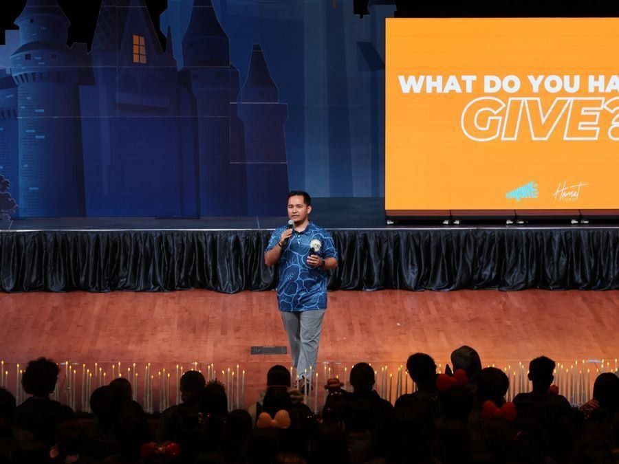 Speaker on a lit stage in front of a full audience