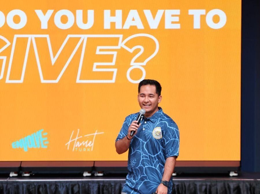 Speaker in front of a large orange event graphic